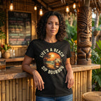 Woman wearing a black t-shirt with a beach and bourbon design, standing in a tropical bar setting.