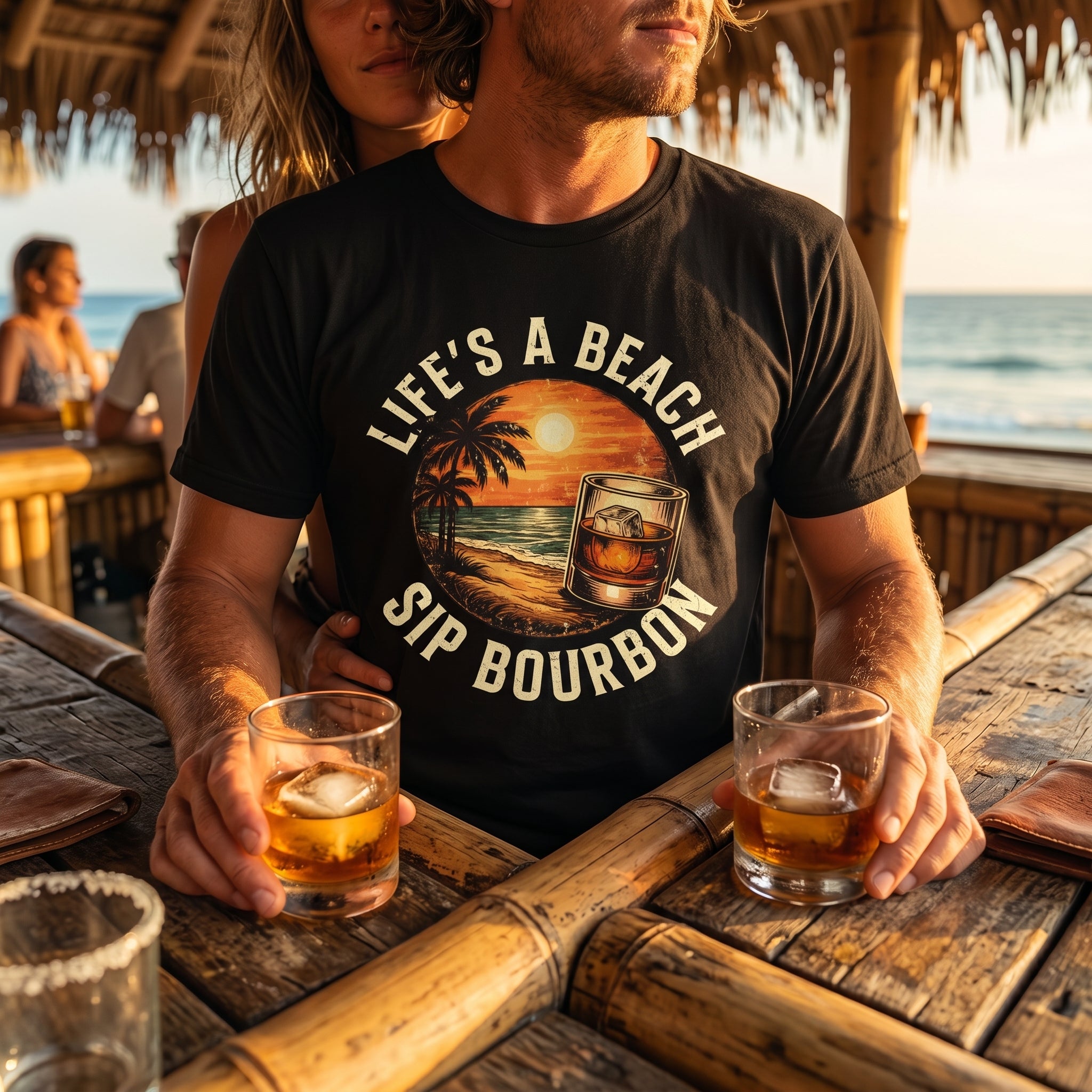 Man wearing a t-shirt with 'Life's a Beach, Sip Bourbon' design at a beach bar.