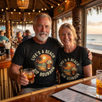 Man and woman wearing matching 'Life's a Beach, Sip Bourbon' shirts in a bar setting with ocean view.